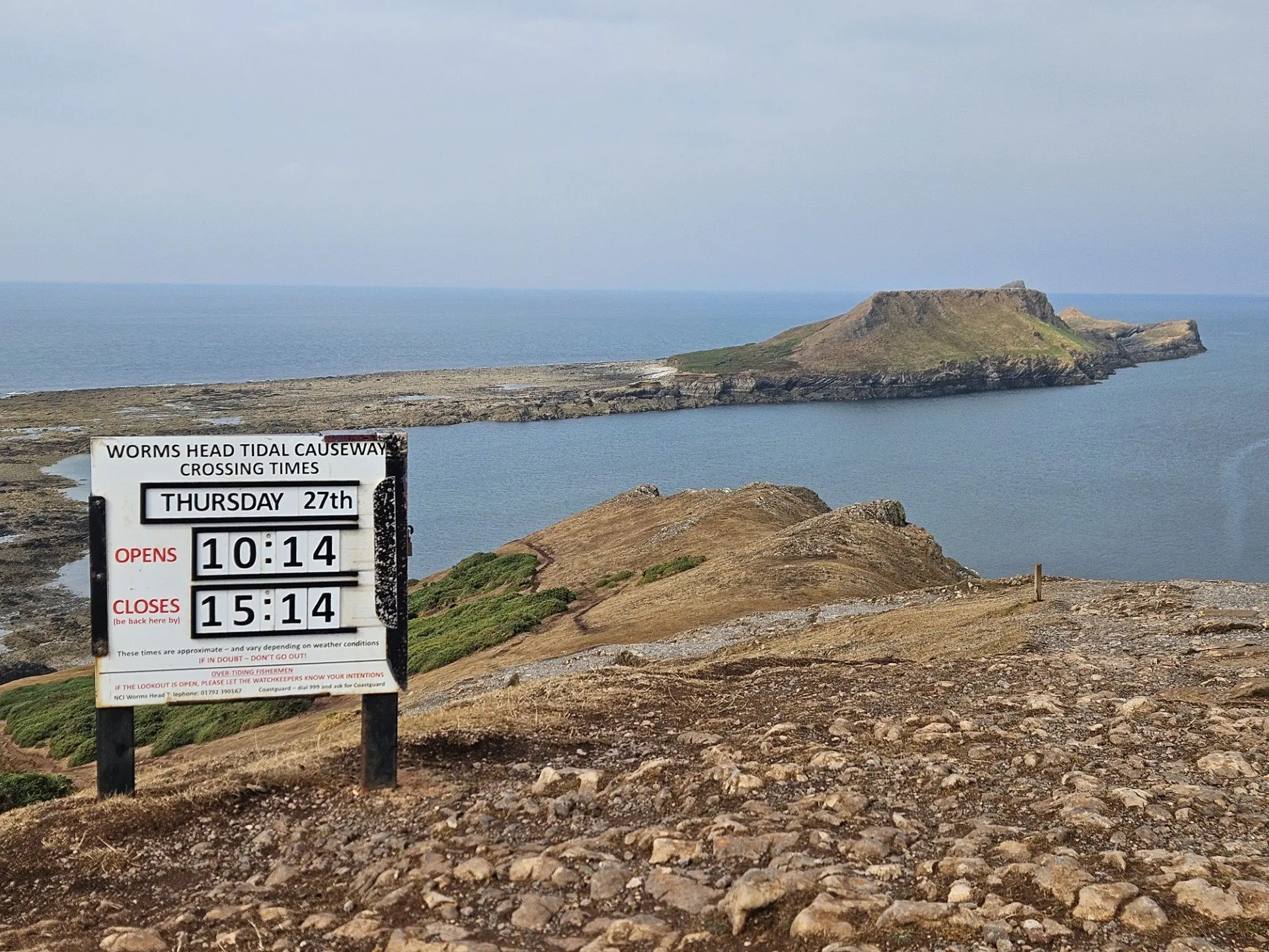 The Worms Head Tidal Causeway crossing times board on the clifftop, showing that day's opening and closing times