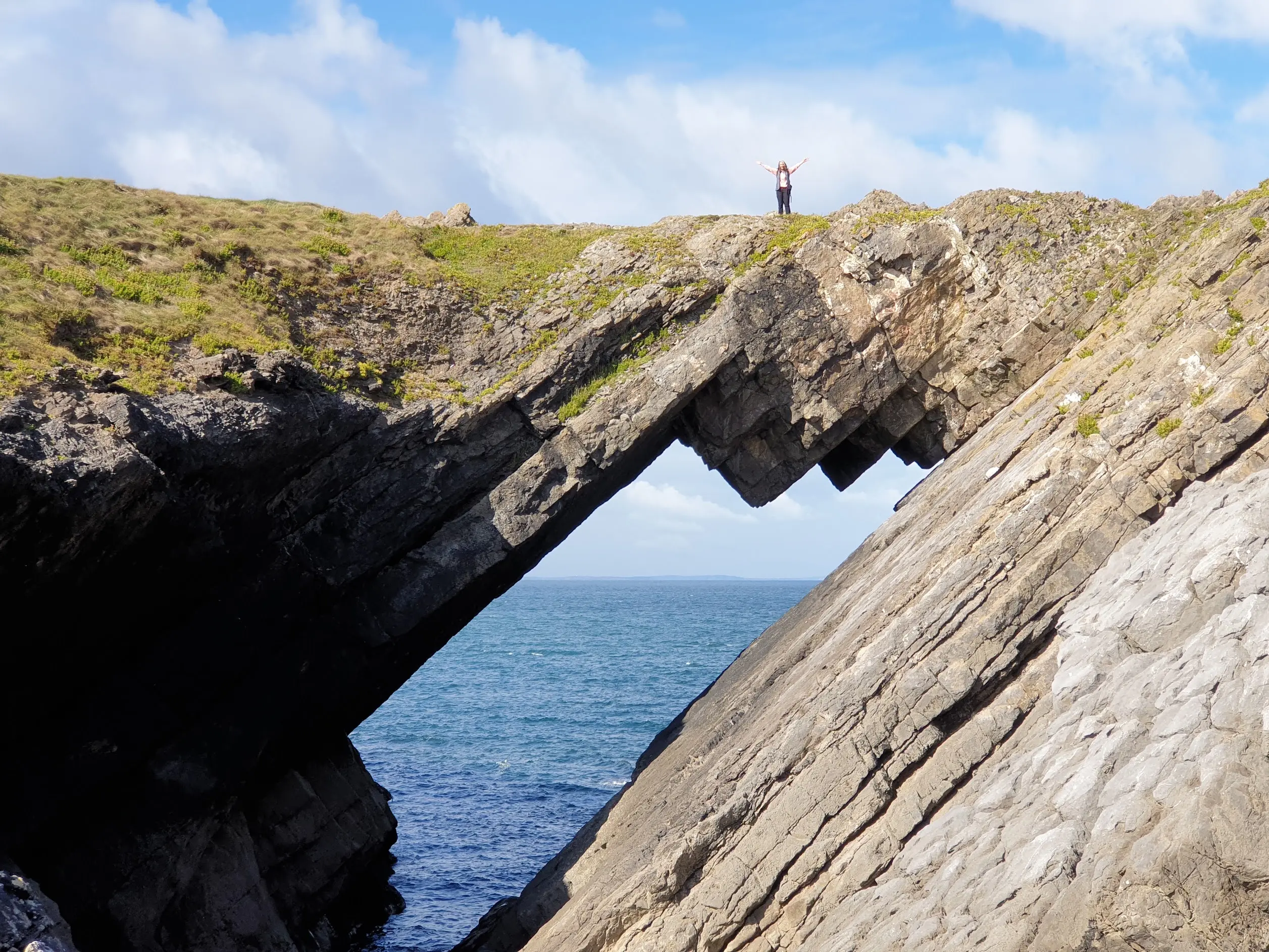 A walker standing atop Devil's Bridge, the natural rock arch on Worms Head