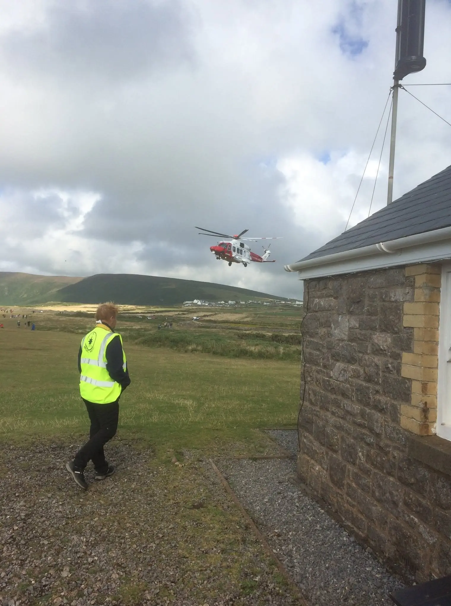 A watchkeeper in hi-vis outside the lookout as the Coastguard rescue helicopter flies in