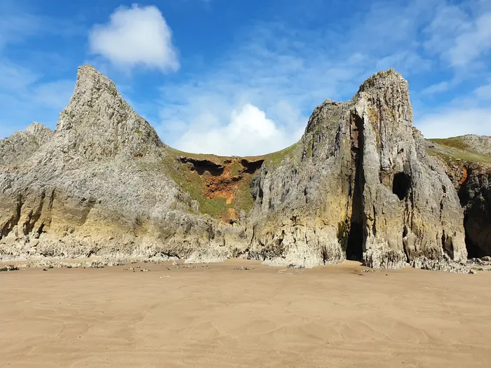 Towering limestone pinnacles and a sea cave above the beach at Mewslade Bay