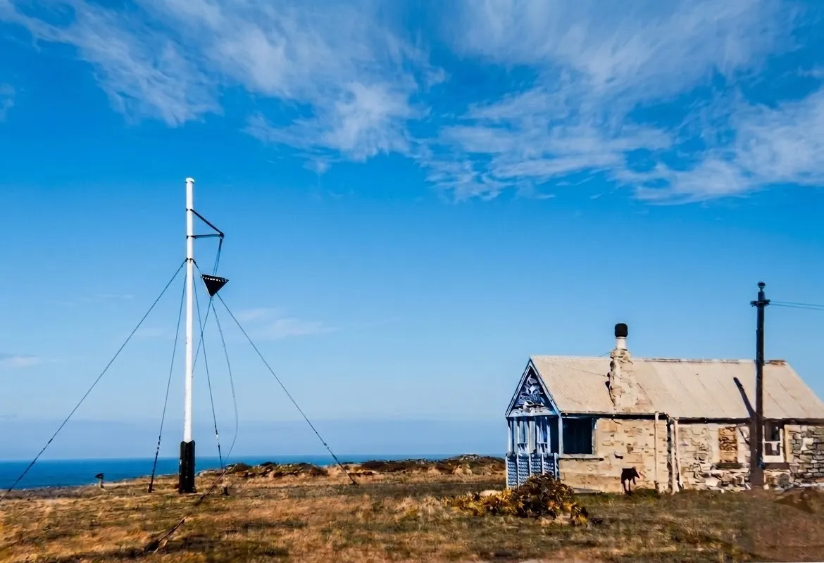 Historic photograph of the old Coastguard lookout at Rhosili, with the weather mast beside it flying a storm cone