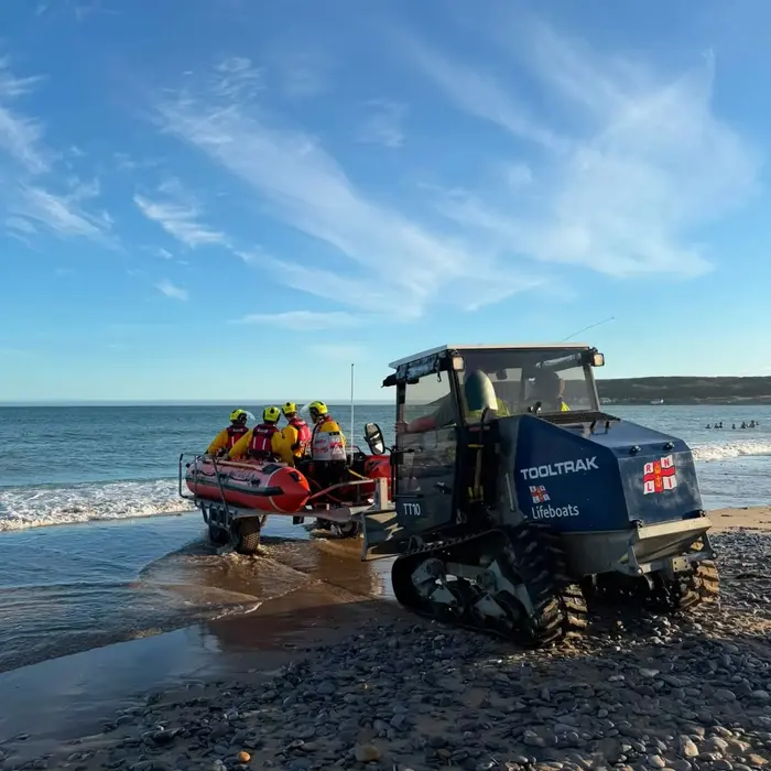 Horton and Port Eynon RNLI crew launching their inshore lifeboat from the beach on a tracked all-terrain vehicle