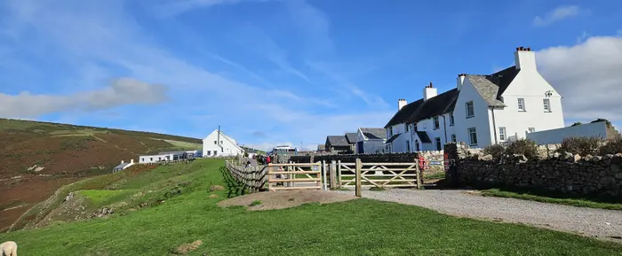 The gate onto the coast path at Rhosili, with whitewashed cottages and Rhosili Down behind