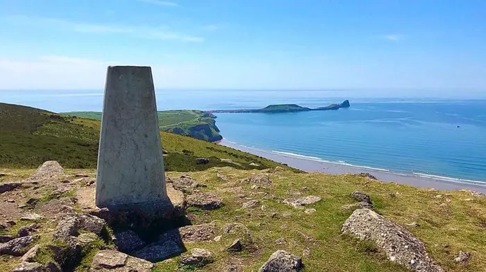 The trig point on top of Rhosili Down, looking over Rhosili Bay to Worms Head