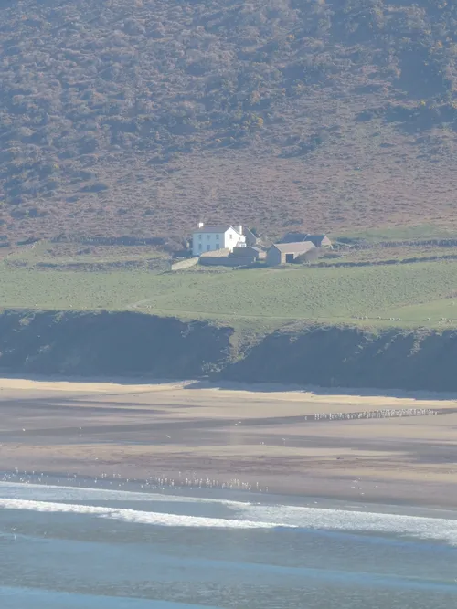 The white Rhosili Old Rectory beneath Rhosili Down, above the beach at Rhosili Bay