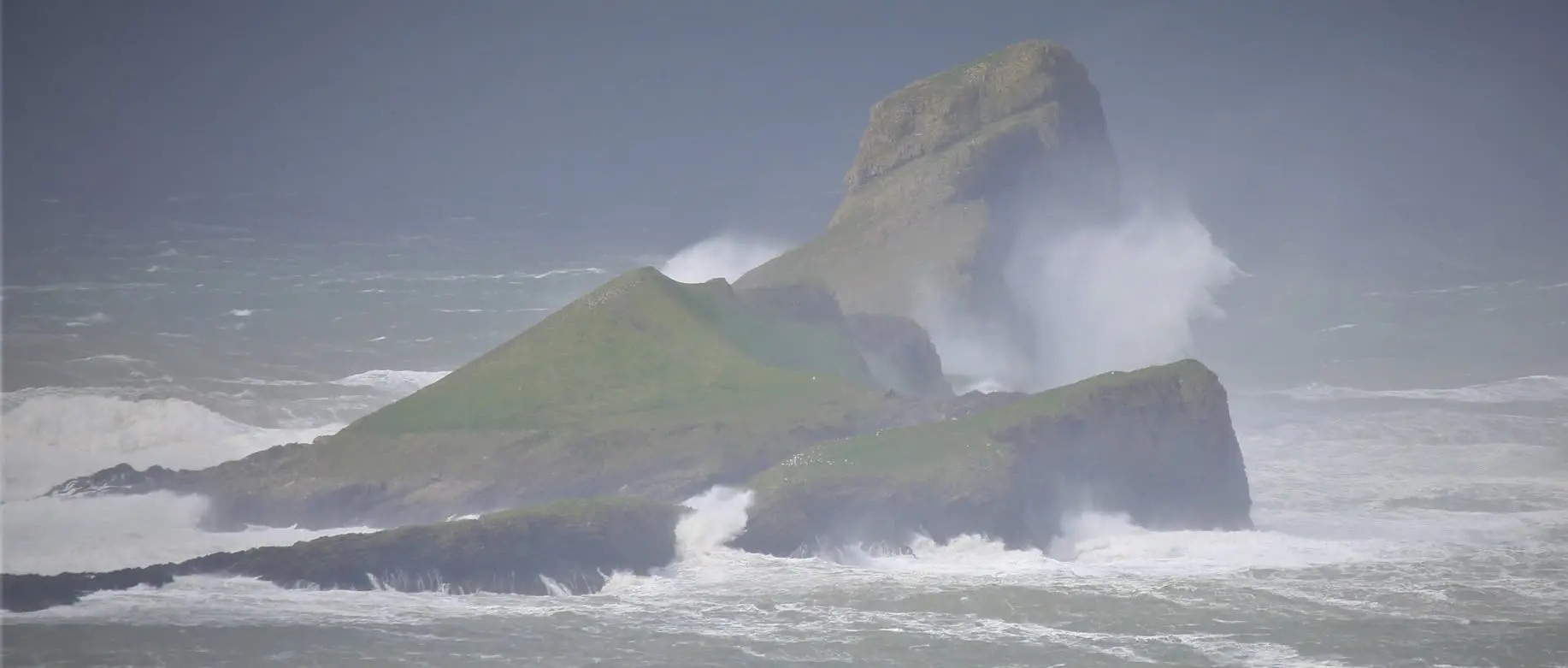 Huge storm waves crashing over Worms Head, showing the power of the sea