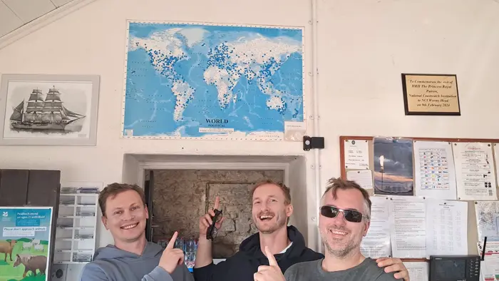 Andrei, Vadim, and a friend pointing at the world visitors map inside the Lookout Station