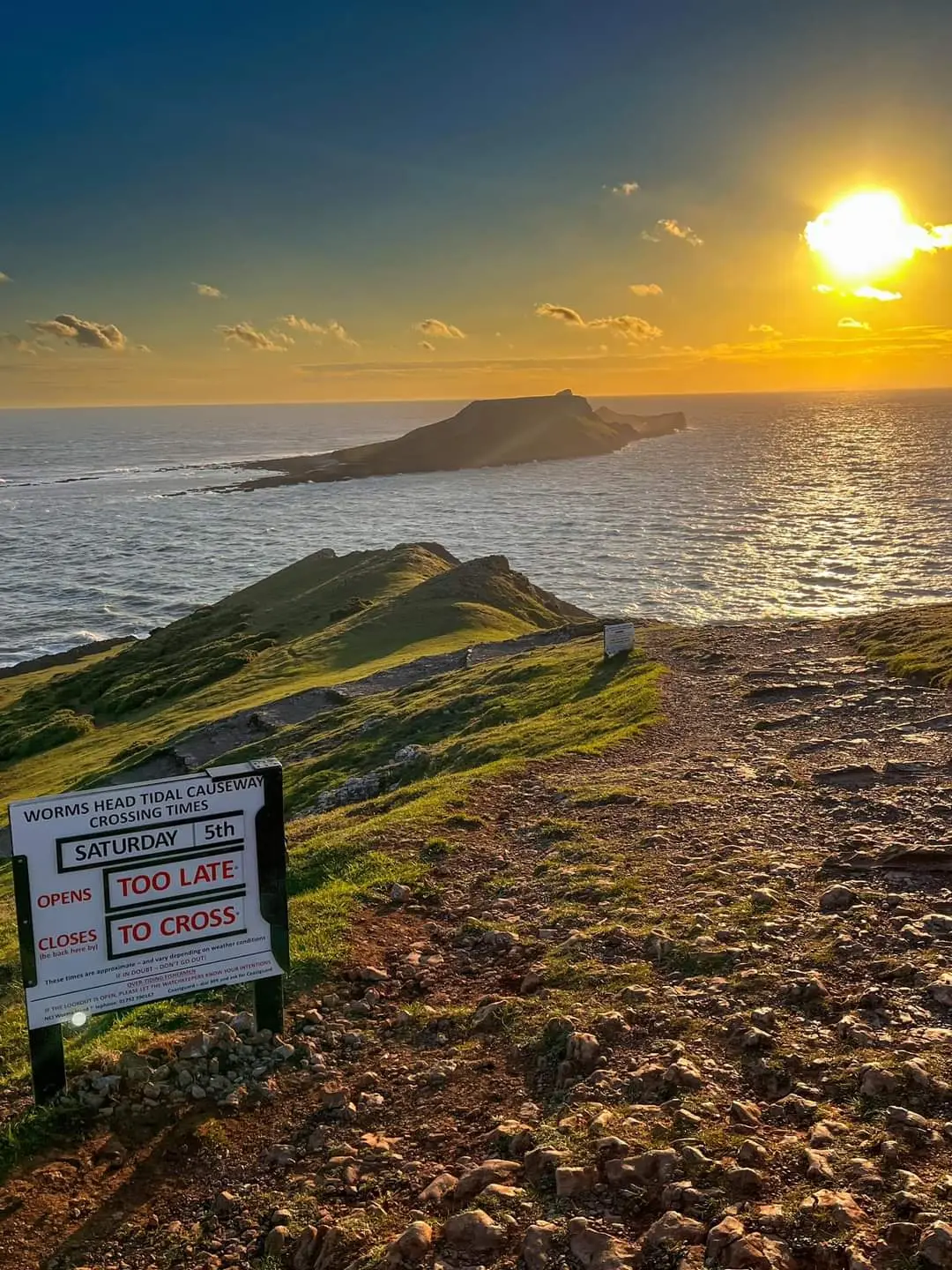 Sunset view of the causeway safety sign warning that it is too late to cross safely
